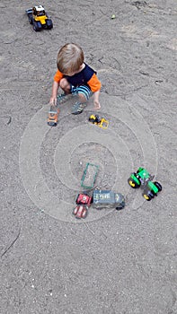 Boy playing in the sand with cars