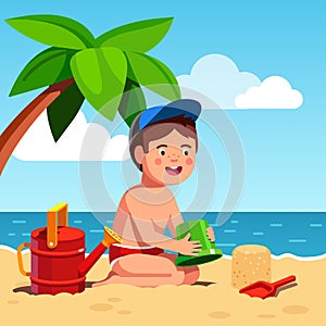 Boy playing sand castles game sitting on sea shore