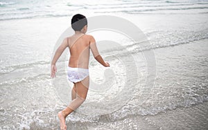 Boy playing  on sandy beach.  Happy kid on vacations at seaside on summer holidays. Children in nature with sea, sand and blue sky