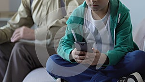 Boy playing on smartphone, ignoring grandfather criticizing him, generation gap