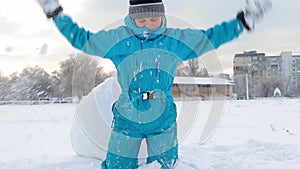 Boy playing in the snow throws a snowball