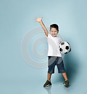 Cute boy playing football, happy child, young male teenager goalkeeper enjoying sports game, holding ball