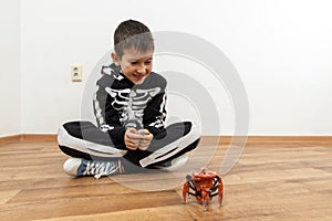 Boy playing with spider robot toy on the floor at home