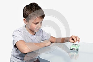 Boy playing sports retrocars on a glass table