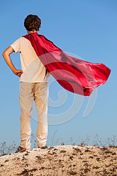 Boy playing superheroes on the sky background,