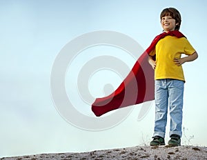 Boy playing superheroes on the sky background, child superhero i
