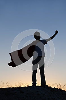 Boy playing superheroes on the sky background, silhouette of tee