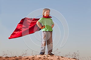 Boy playing superheroes on the sky background, teenage superhero