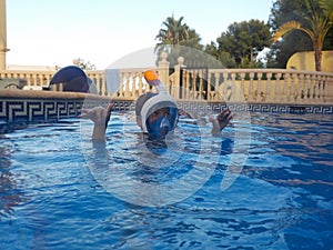 A boy is playing in a swimming pool with Easybreath mask