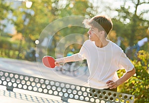 boy playing table tennis ping pong outdoors