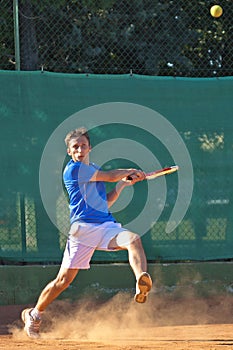 Boy playing tennis hitting the ball with backhand