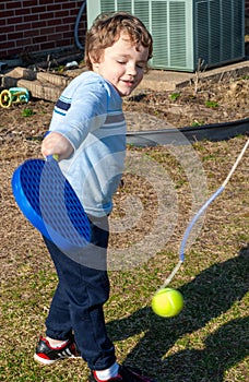 Boy playing tether ball in yard photo