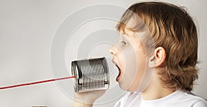 Boy Playing with Tin Can Phone. Isolated on Orange Background