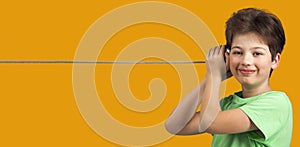 Boy Playing with Tin Can Phone. Isolated on Orange Background