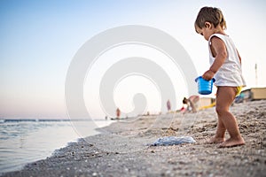 Boy playing with toys on the beach building beads and turrets smiling at someone behind the scenes on summer vacation