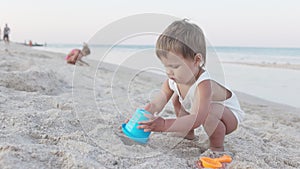 Boy playing with toys on the beach building beads and turrets smiling at someone behind the scenes on summer vacation