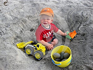 Boy playing with trucks at the beach