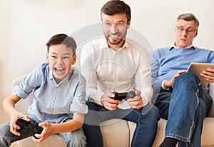 Boy Playing Video Games With Dad And Grandpa At Home