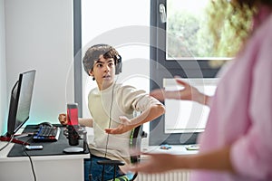 Boy playing video games while his mother is not happy about it