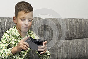Boy playing video games with joystic sitting on sofa