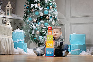 Boy playing with wooden alphabet blocks against Christmas tree