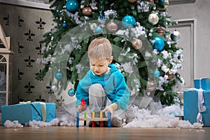 Boy playing with wooden hammer toy while sitting beside Christmas tree