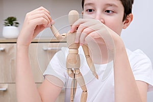 A boy playing wooden mannequin, articulated doll at home, kid, child trying different poses and roles of people