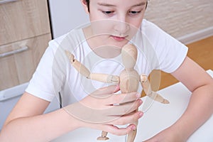 A boy playing wooden mannequin, articulated doll at home, kid, child trying different poses and roles of people