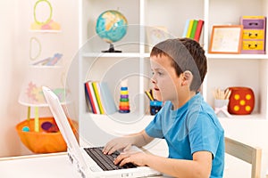 Boy playing or working on laptop computer