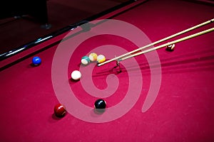 Boy plays billiard or pool in club. Young Kid learns to play snooker. Boy with billiard cue strikes the ball on table.