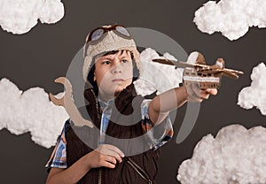 A boy plays with a cardboard airplane and wrench and dreams of becoming a pilot, dressed in a retro style jacket and helmet with