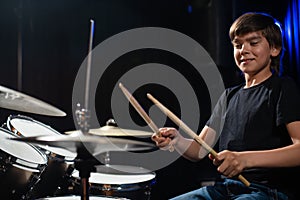 A boy plays drums in a recording studio