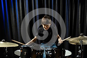 A boy plays drums in a recording studio