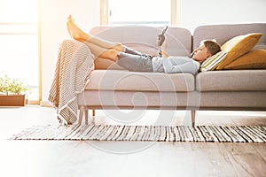 Boy plays with electronic devices - gamepad connected with smartphone lying on the cozy sofa in the home living room photo