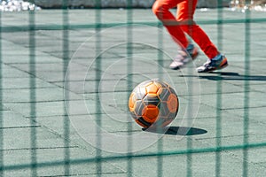 A boy plays football alone and kicks the ball, a soccer ball in a children`s play stadium