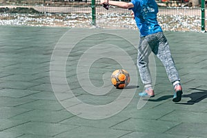 A boy plays football alone and kicks the ball, a soccer ball in a children`s play stadium
