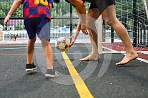 Boy plays football with his father on the outdoor playing field.