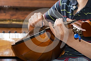 The boy plays the guitar and takes chords, dombra on the background of the piano.