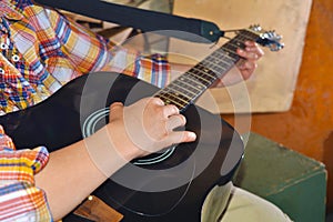 The boy plays the guitar and takes chords, dombra on the background of the piano.