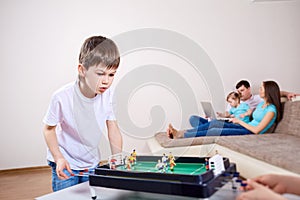 Boy plays at home in board games. Parents relax