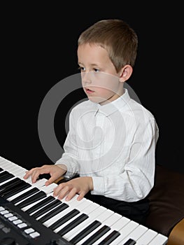 Boy plays keyborad, piano, looking in notes sheet photo