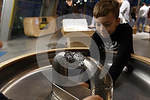 A boy plays with metal objects on a stand with a large magnet