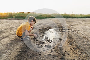 A boy in an plays with mud in the ground in nature. lifestyle