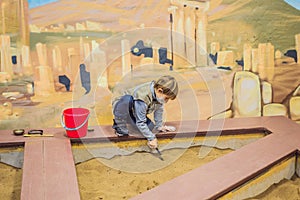 A boy plays a paleontologist, looking for ancient finds in the ground