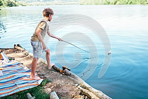 Boy plays with paper boat and launches it on the lake