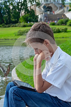 The boy plays in phone in the park