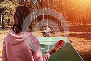 A boy plays ping pong with his mom, sports games. The concept of family ties, intergenerational communication, parents and