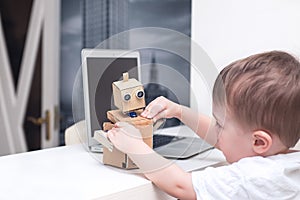 Boy plays with the robot on a white table at home