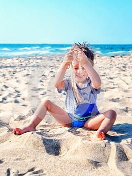 Boy plays with sand by the sea