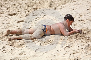 A boy plays in the sand on the seashore
